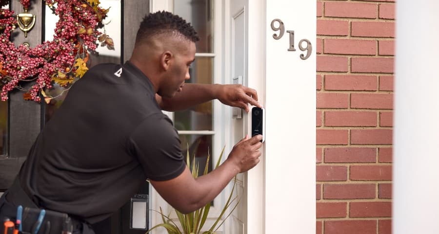 Vivint team member installing a video doorbell on the outside of a home